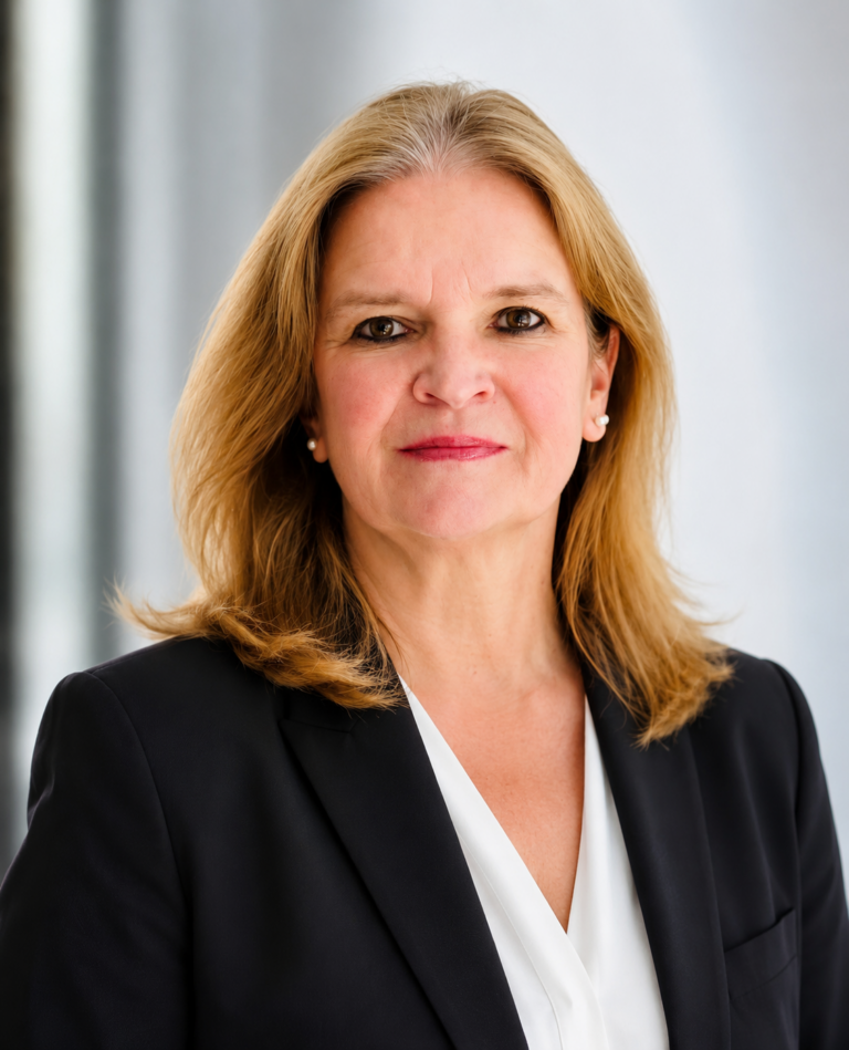 Professional headshot of a smiling blonde woman in a black blazer and white blouse.