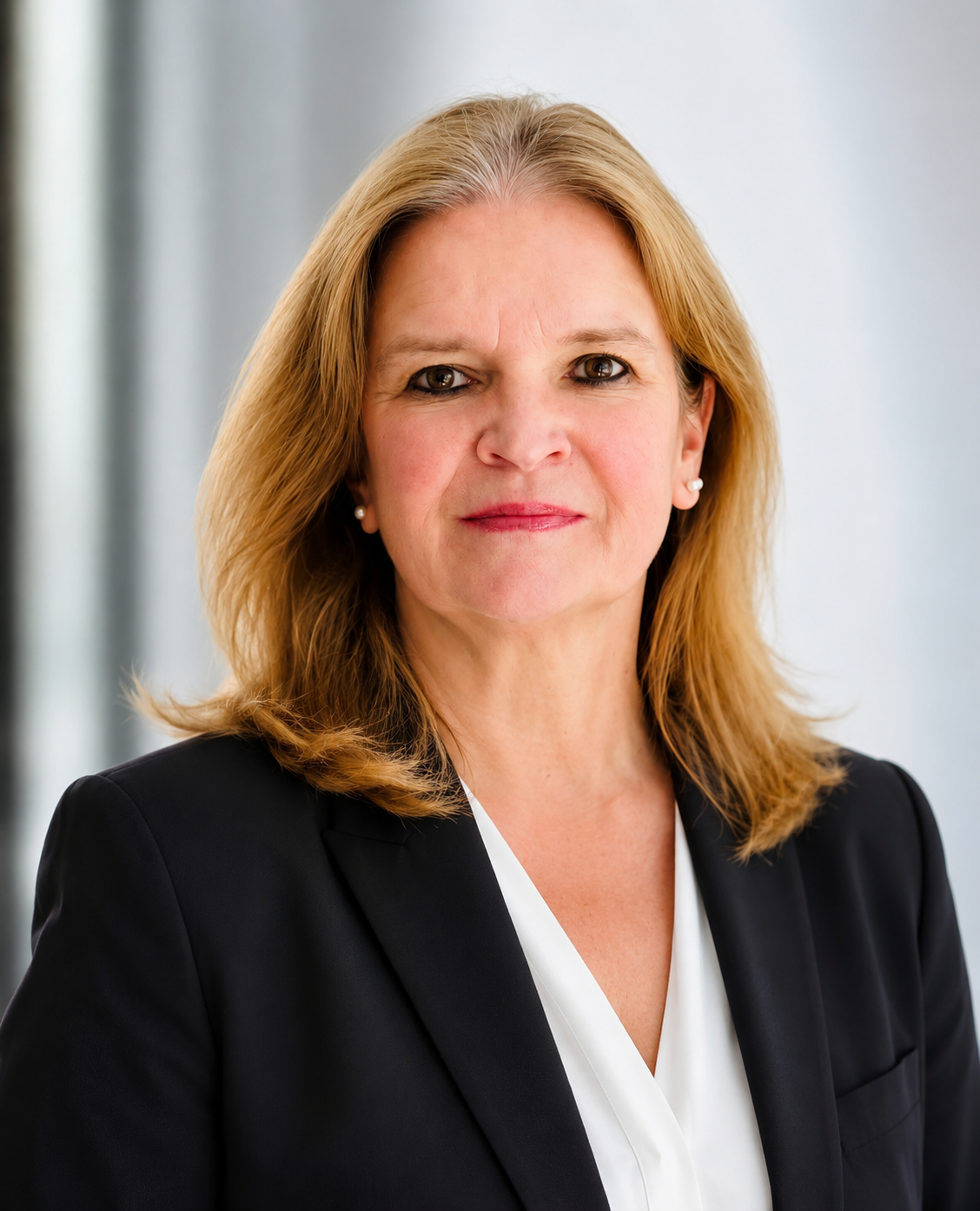 Professional headshot of a smiling blonde woman in a black blazer and white blouse.